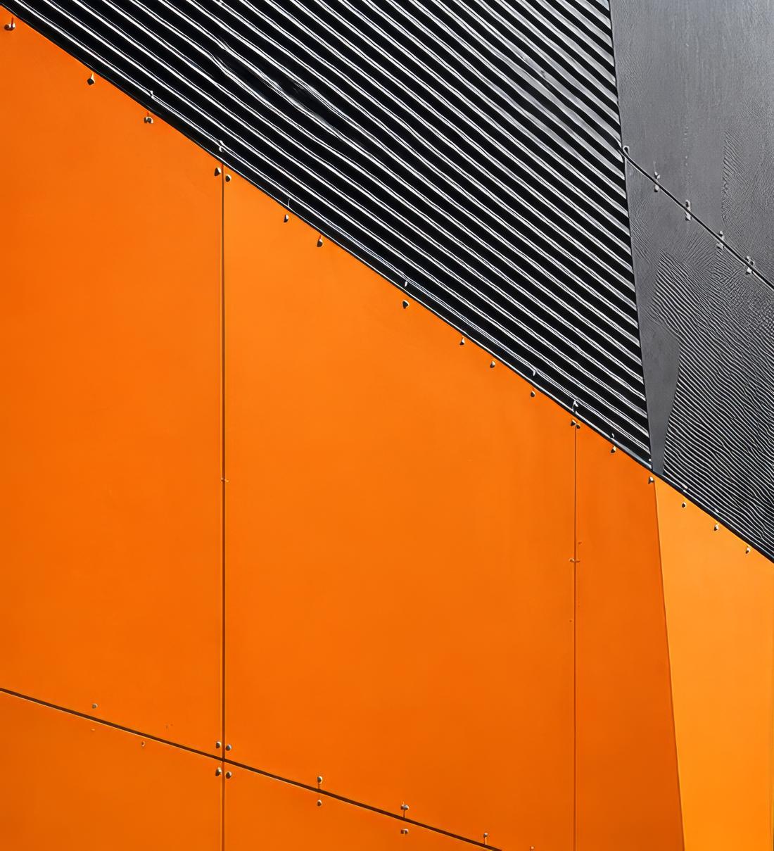 Détail de façade en panneaux orange et bardage anthracite